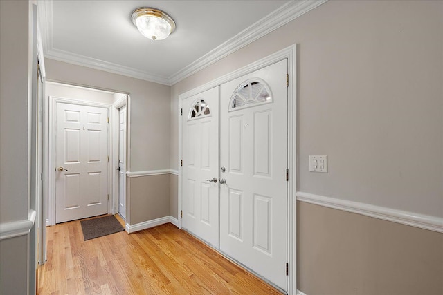 foyer with light wood-style floors, baseboards, and ornamental molding