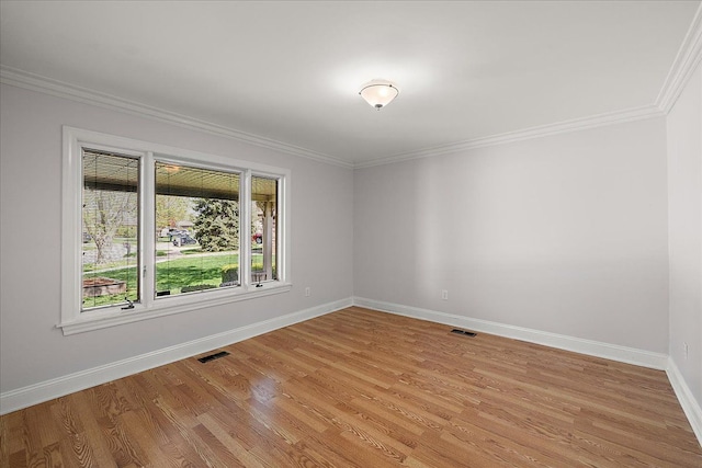 unfurnished room with crown molding, baseboards, light wood-type flooring, and visible vents