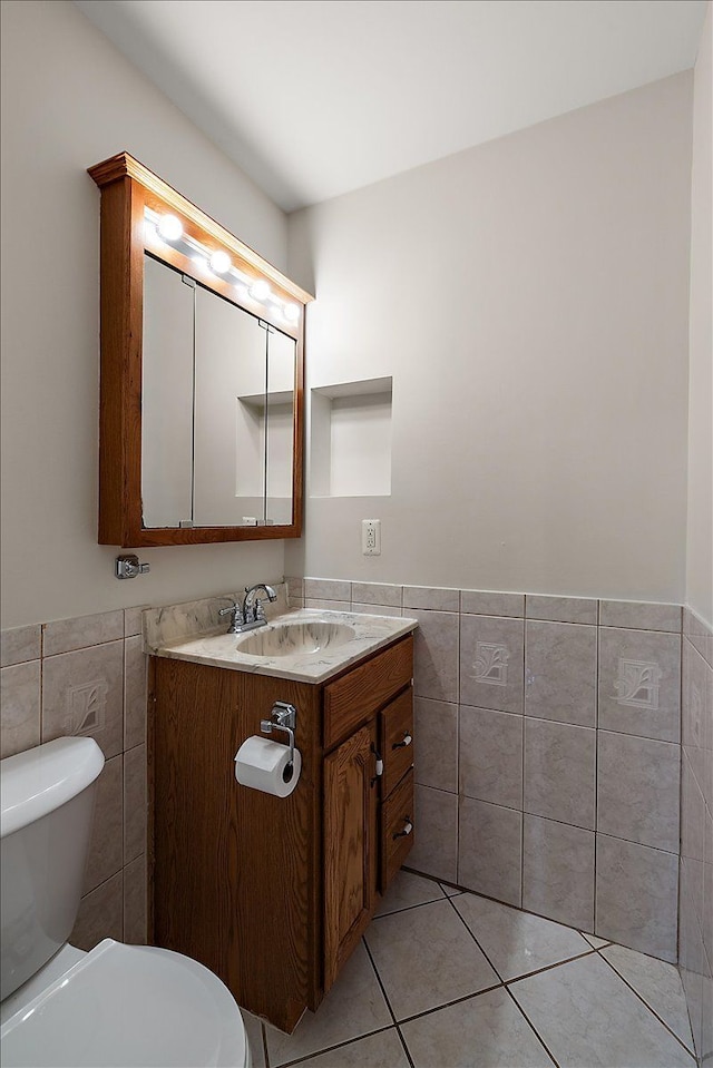 bathroom with wainscoting, toilet, and tile walls