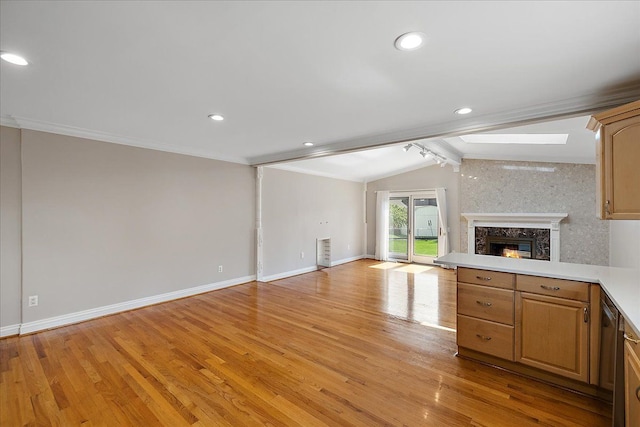 unfurnished living room featuring crown molding, lofted ceiling with beams, a premium fireplace, baseboards, and light wood-type flooring