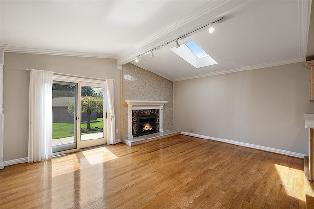 unfurnished living room featuring light wood-type flooring, rail lighting, baseboards, and a high end fireplace