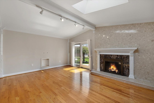 unfurnished living room with track lighting, wood finished floors, lofted ceiling with skylight, and a high end fireplace