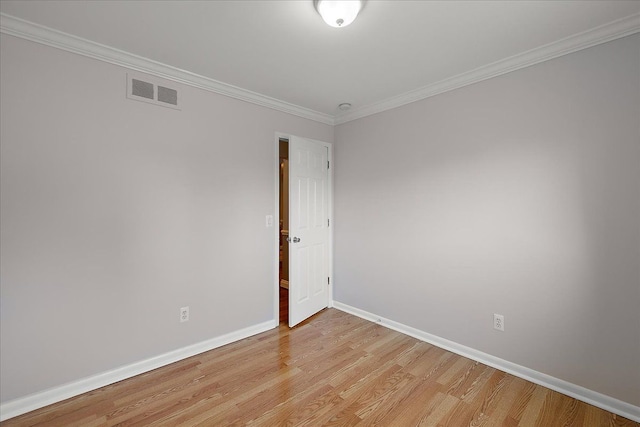 spare room with crown molding, baseboards, light wood-type flooring, and visible vents