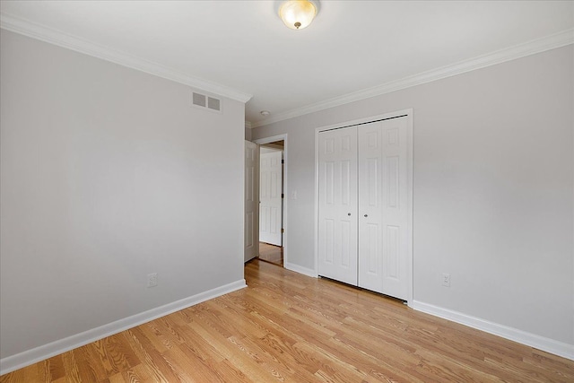 unfurnished bedroom with baseboards, ornamental molding, light wood-style flooring, and visible vents