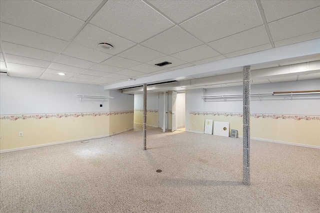 finished below grade area with baseboards, visible vents, a paneled ceiling, and carpet