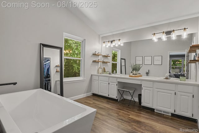 1710 Dawncrest Dr, West Bloomfield, MI 48324 - full bath featuring double vanity, a freestanding tub, wood finished floors, vaulted ceiling, and plenty of natural light