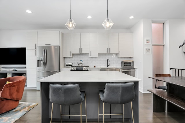 kitchen featuring a sink, tasteful backsplash, stainless steel appliances, and a kitchen bar