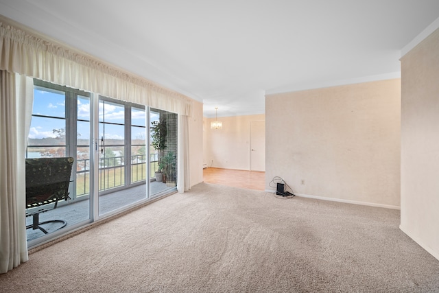 unfurnished living room featuring carpet flooring, baseboards, a chandelier, and ornamental molding