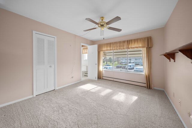 unfurnished bedroom featuring carpet floors, a ceiling fan, baseboards, and a baseboard radiator