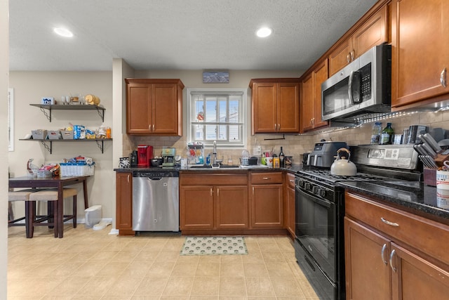 kitchen featuring brown cabinets, stainless steel appliances, decorative backsplash, and a sink