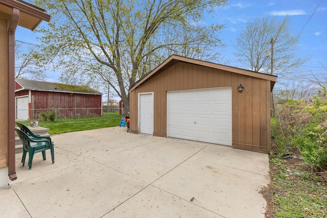 detached garage featuring fence and concrete driveway