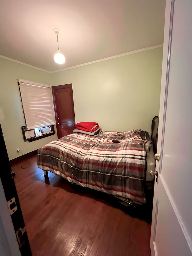 bedroom with crown molding, baseboards, and wood finished floors