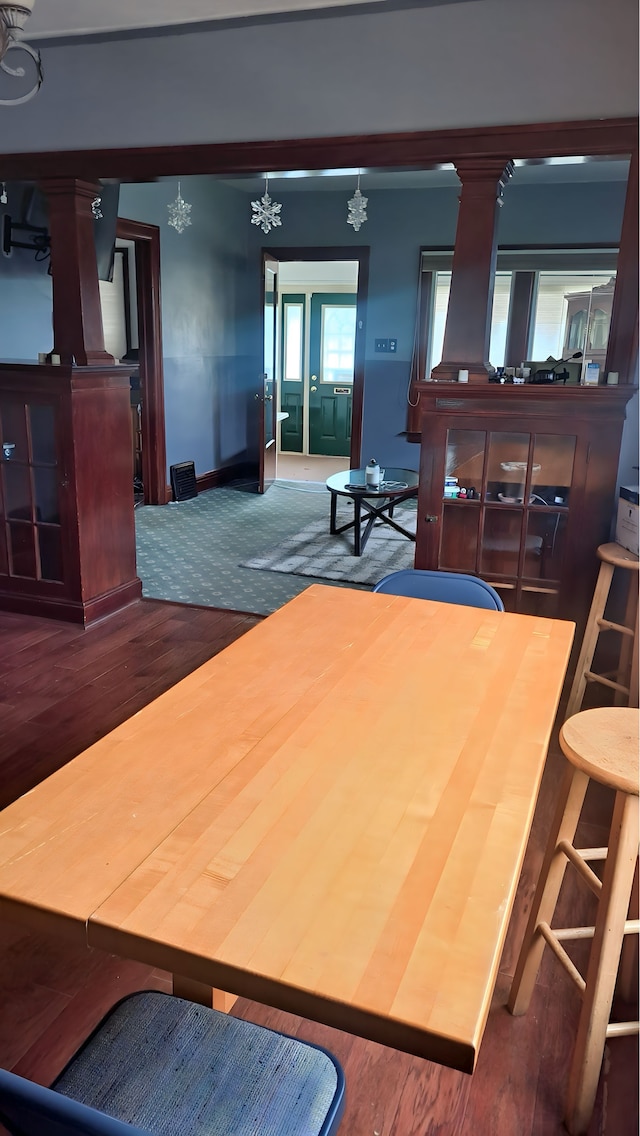 dining room featuring baseboards, an inviting chandelier, ornate columns, and wood finished floors