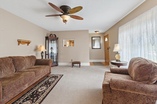 living area featuring light colored carpet, baseboards, and ceiling fan