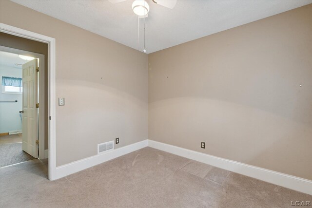 carpeted spare room featuring visible vents, a ceiling fan, and baseboards