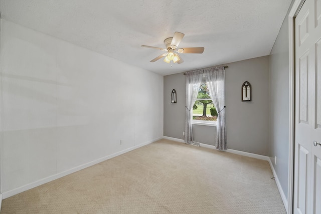 unfurnished room featuring light colored carpet, a ceiling fan, baseboards, and a textured ceiling