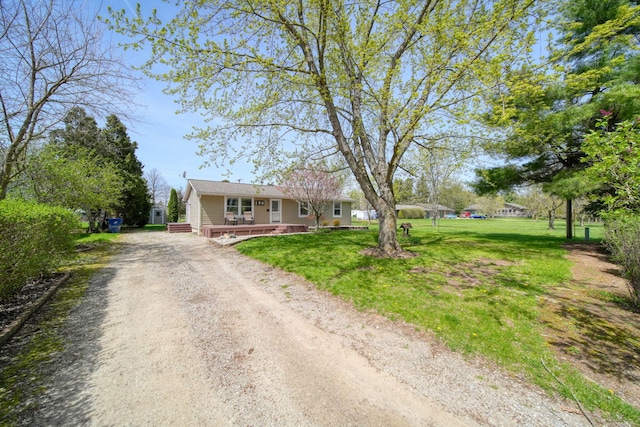 view of front of property featuring a deck, driveway, and a front yard