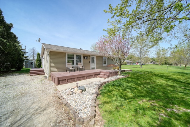 rear view of house featuring a lawn, a storage unit, an outbuilding, and a deck