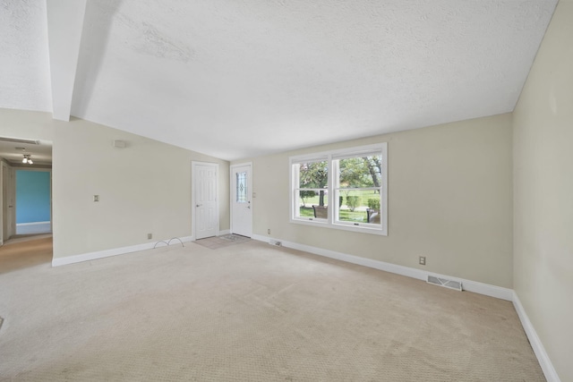 empty room with visible vents, a textured ceiling, vaulted ceiling with beams, and light colored carpet