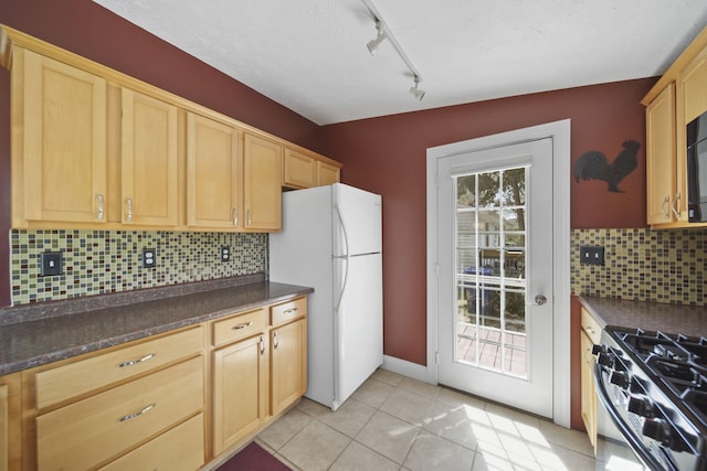 kitchen featuring freestanding refrigerator, dark countertops, light tile patterned floors, and light brown cabinets
