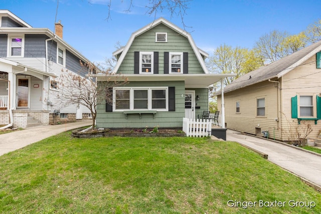 colonial inspired home with a gambrel roof, a front lawn, and covered porch