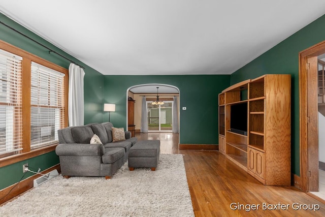 living room with arched walkways, baseboards, visible vents, and wood finished floors