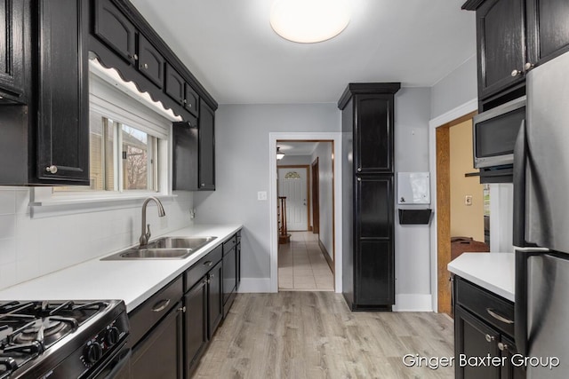 kitchen featuring a sink, appliances with stainless steel finishes, backsplash, and light countertops