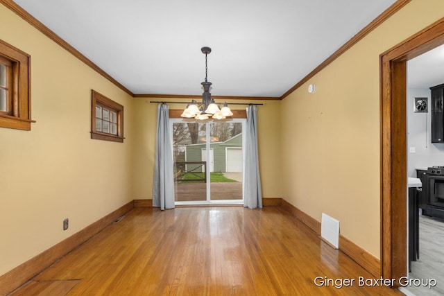 unfurnished dining area featuring baseboards, ornamental molding, light wood-style flooring, and a chandelier