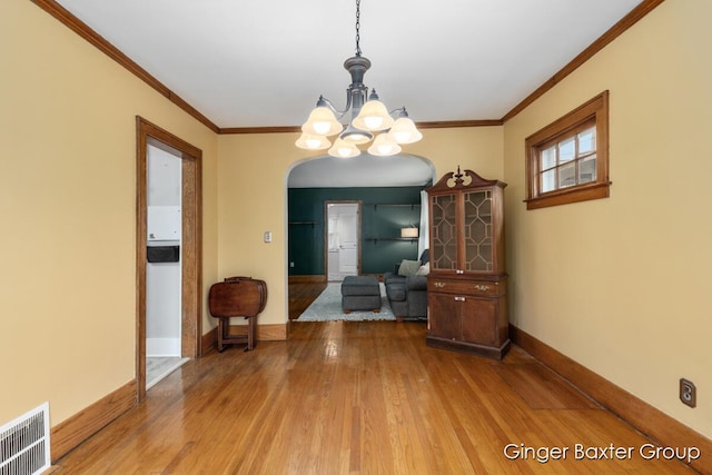 dining space featuring visible vents, arched walkways, wood finished floors, baseboards, and an inviting chandelier