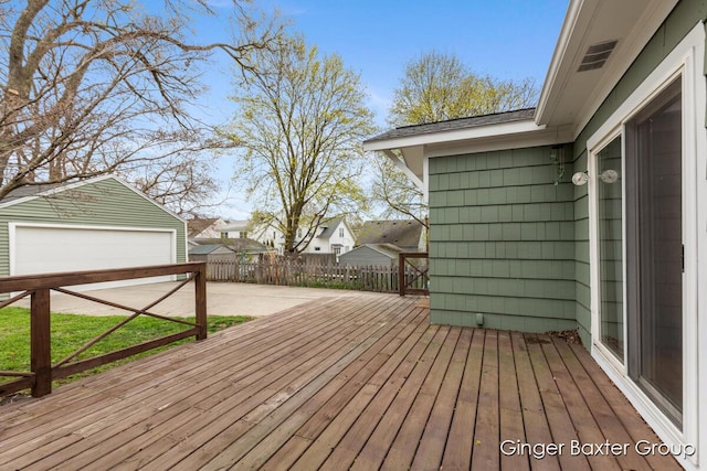 wooden terrace featuring an outdoor structure, a garage, and fence