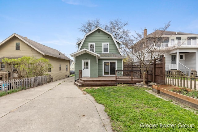 dutch colonial featuring a garden, fence, a front yard, a deck, and a gambrel roof