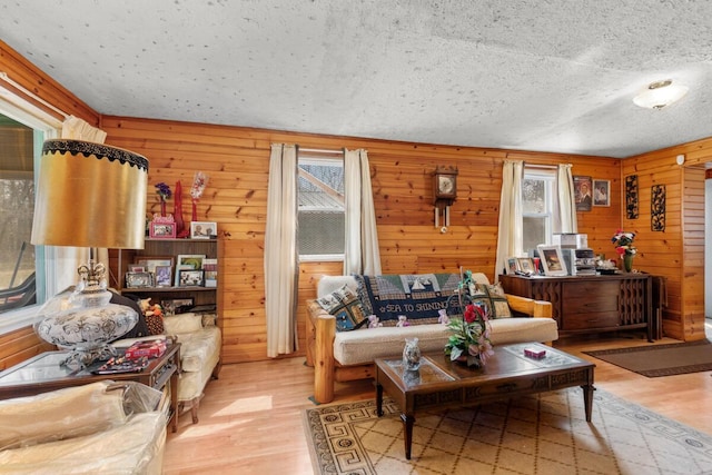 living room featuring wooden walls, a healthy amount of sunlight, and wood finished floors