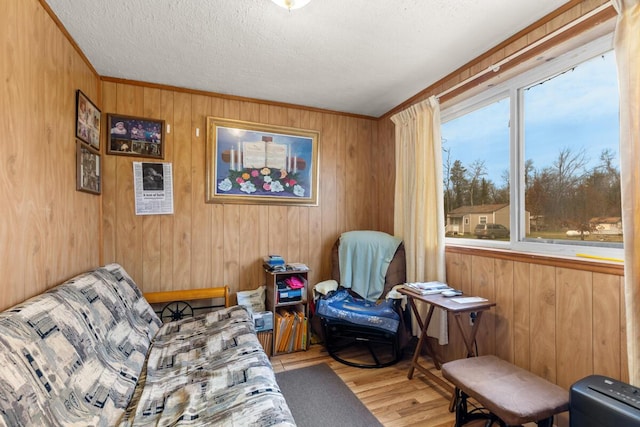 living area with a textured ceiling, wood finished floors, and wooden walls