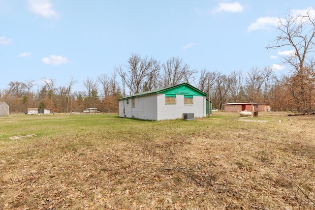 view of property exterior with concrete block siding, central AC unit, and a yard
