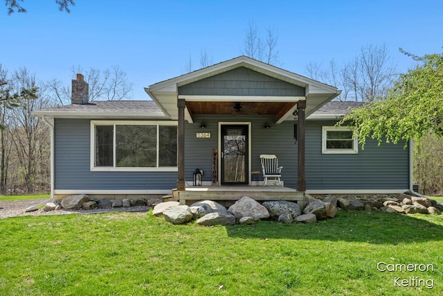 single story home with covered porch, roof with shingles, a chimney, and a front yard