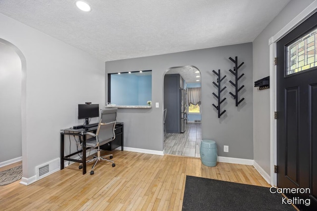 home office featuring visible vents, arched walkways, wood-type flooring, and baseboards