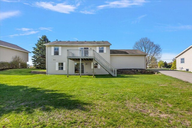 rear view of property featuring stairs, a wooden deck, and a yard