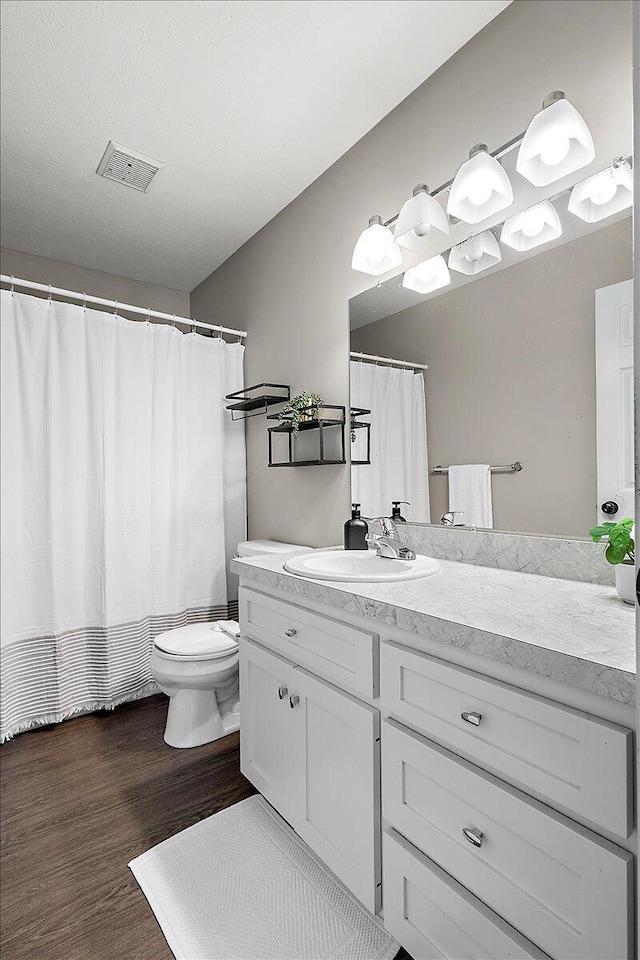 full bath featuring visible vents, wood finished floors, toilet, and vanity
