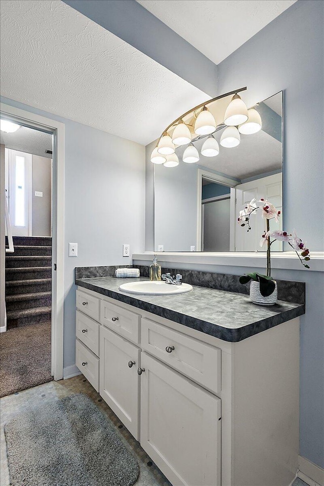 bathroom with vanity, a textured ceiling, and baseboards