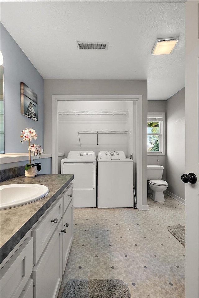 bathroom with washer and dryer, vanity, toilet, baseboards, and visible vents