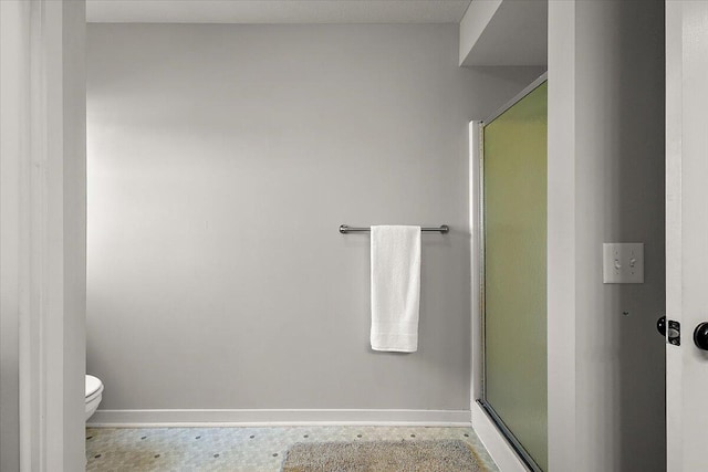 full bath featuring toilet, baseboards, and a stall shower
