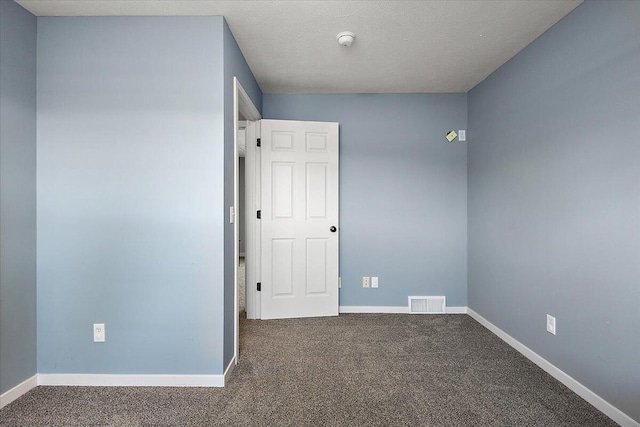 empty room featuring carpet floors, baseboards, and visible vents