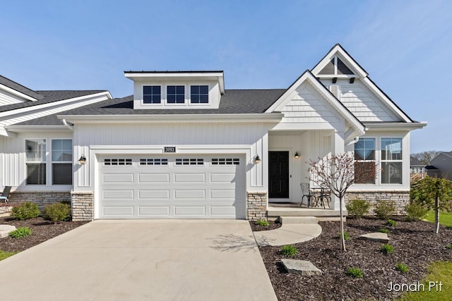 craftsman-style home with a garage, board and batten siding, driveway, and stone siding