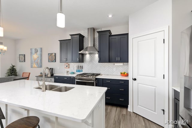 kitchen featuring a breakfast bar area, backsplash, a sink, stainless steel range with gas cooktop, and wall chimney exhaust hood