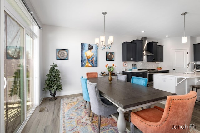 dining space featuring an inviting chandelier, baseboards, light wood-style floors, and recessed lighting