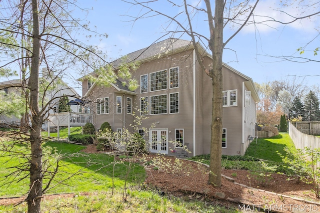 rear view of house with a yard, fence, and french doors