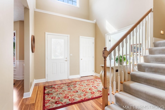 foyer with baseboards, a towering ceiling, wood finished floors, and stairway