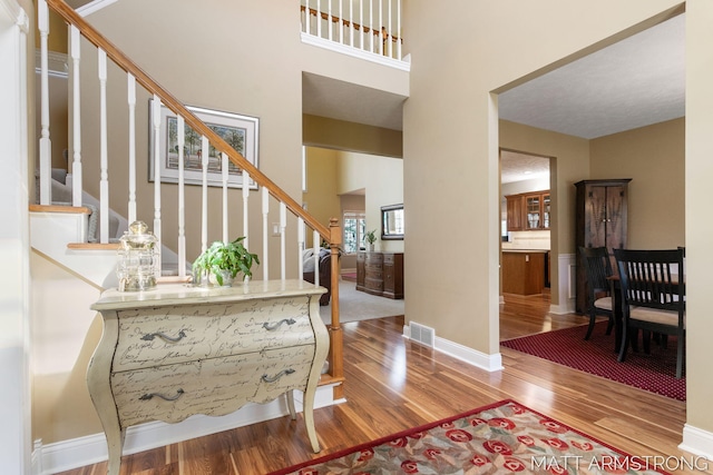 foyer with baseboards, visible vents, wood finished floors, and stairway