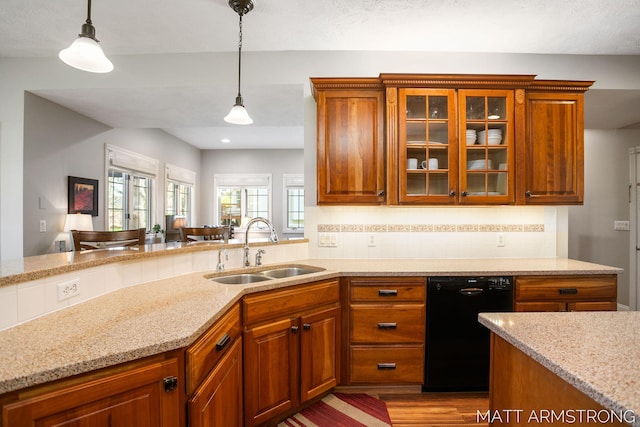 kitchen with a sink, light stone counters, decorative light fixtures, and dishwasher
