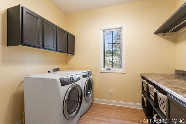 laundry area featuring cabinet space, baseboards, washer and clothes dryer, and light wood-style flooring